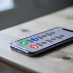 Que faire après plusieurs appels inconnus sans message vocal Un smartphone posé sur une table en bois, affichant plusieurs notifications abstraites d’appels manqués dans une ambiance réaliste et sobre.