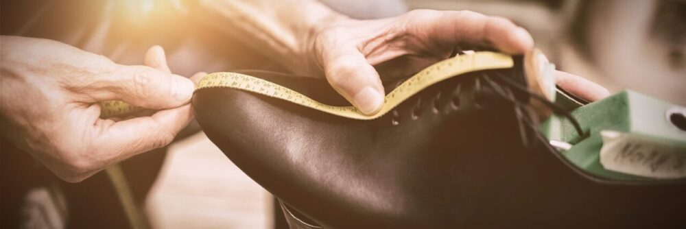 Une personne mesure son pied avec une règle pour comparer les tailles de chaussures européennes et américaines.